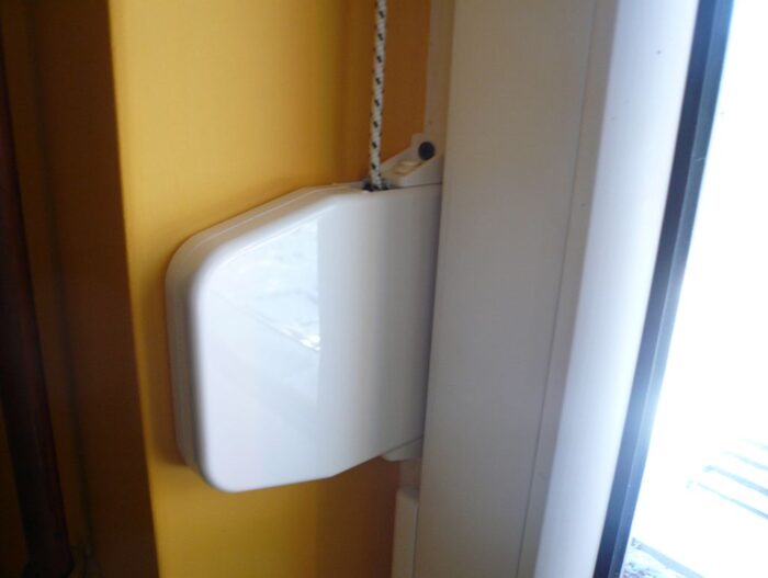 P1070601 Na stronie internetowej poświęconej naprawom bram, rolet i barier w Warszawie znajdziesz zdjęcie przedstawiające elegancki biały czujnik drzwi zainstalowany obok żółtej ściany. Ten czujnik jest przymocowany obok nieskazitelnej białej ramy drzwi za pomocą charakterystycznego czarno-białego przewodu. Błyszczące wykończenie czujnika elegancko odbija światło, podkreślając jego cel, jakim jest zwiększenie bezpieczeństwa drzwi, nad którymi sprawuje nadzór.