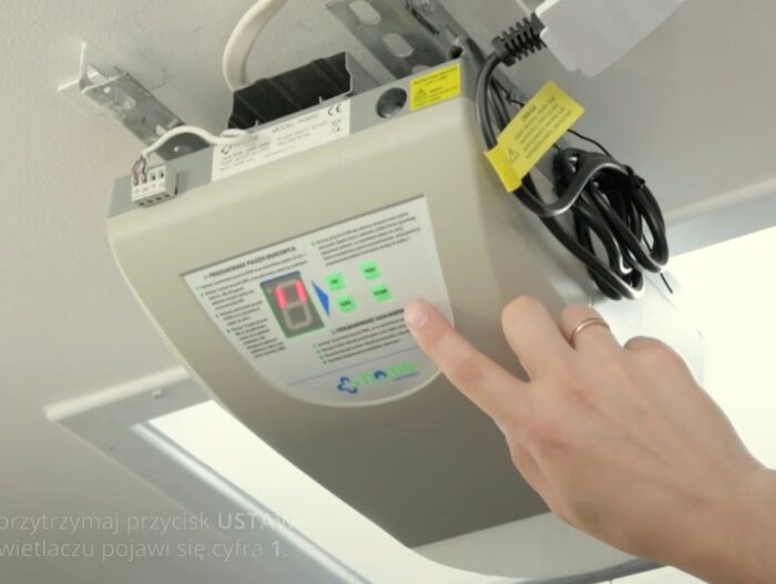 maxresdefault Obraz na stronie internetowej poświęconej naprawie bram, rolet i barier w Warszawie przedstawia szczegółowy widok osoby obsługującej urządzenie sterujące zamontowane na ścianie, wyposażone w ekran i kilka przycisków. Widać rękę naciskającą jeden z przycisków na tym panelu. Po lewej stronie można zaobserwować kilka kabli. W lewym dolnym rogu obrazu częściowo widoczny jest fragment tekstu w języku polskim.