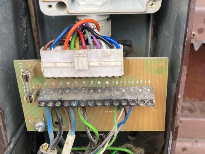 WhatsApp Image 2024-08-04 at 15.38.00 Na stronie internetowej poświęconej naprawom bram, rolet i barier w Warszawie, na obrazie przedstawiono szczegółowy widok panelu elektrycznego. Płytka drukowana jest wyraźnie eksponowana z szeregiem kolorowych przewodów starannie podłączonych do bloku zacisków. Każdy przewód jest wyraźnie oznaczony od 1 do 14, aby ułatwić identyfikację. Na niektórych elementach można zobaczyć cienką warstwę kurzu, co sugeruje potrzebę skorzystania z usług konserwacyjnych lub naprawczych oferowanych przez stronę.