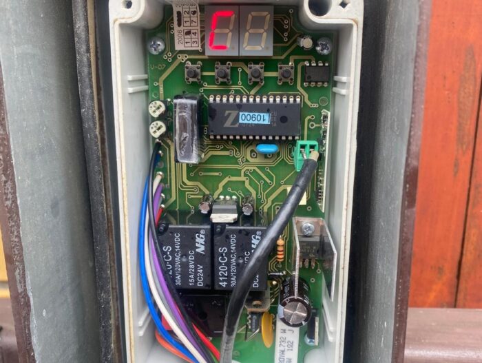 WhatsApp Image 2024-08-04 at 15.38.16 Na zdjęciu widać szczegółowy widok otwartej skrzynki sterowania elektronicznego powszechnie stosowanej w systemach bram, rolet i barier. Wewnątrz widać płytkę drukowaną z różnymi komponentami i przewodami łączącymi. Cyfrowy wyświetlacz wyraźnie wyświetla kod „C8”. Podkreśla to skomplikowaną mechanikę tych rozwiązań bezpieczeństwa, które zazwyczaj są serwisowane i naprawiane przez profesjonalistów w Warszawie.