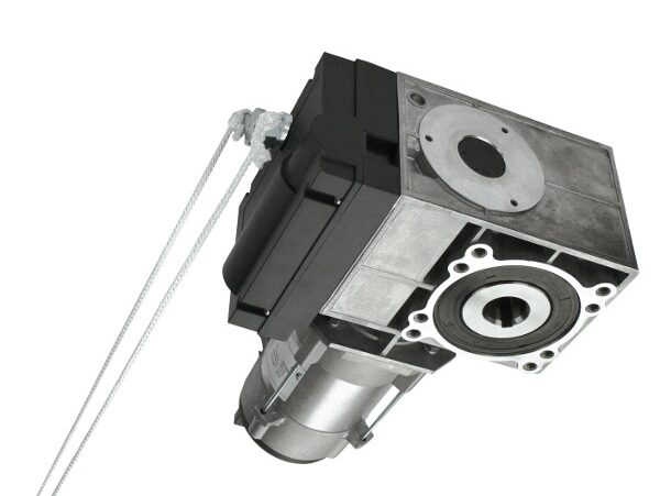 naped-do-bram-przemyslowych-tom Obraz na stronie internetowej poświęconej naprawie bram, rolet i barier w Warszawie przedstawia solidny silnik przekładniowy zamknięty w metalowej obudowie. Na jego czele znajduje się układ kół pasowych przeplatany zwiniętym kablem. Urządzenie jest fachowo ustawione pod kątem, aby podkreślić jego skomplikowaną geometryczną konstrukcję i odrębne komponenty.